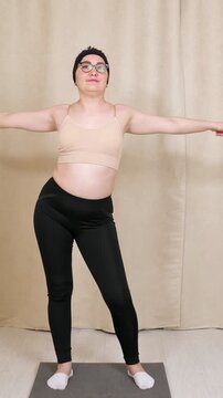 Positive woman in sportswear practicing fitness at home, doing arm rotation exercises to warm up her shoulder joints, improve mobility, and maintain a healthy active lifestyle