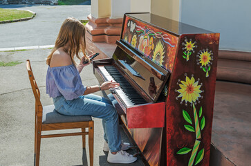 A girl plays a street piano in a city park © batya
