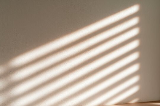 Sunlight casting a blurred window shadow on a neutral white wall background