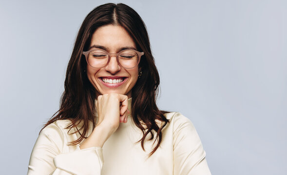 Woman smiling with eyes closed wearing glasses in studio