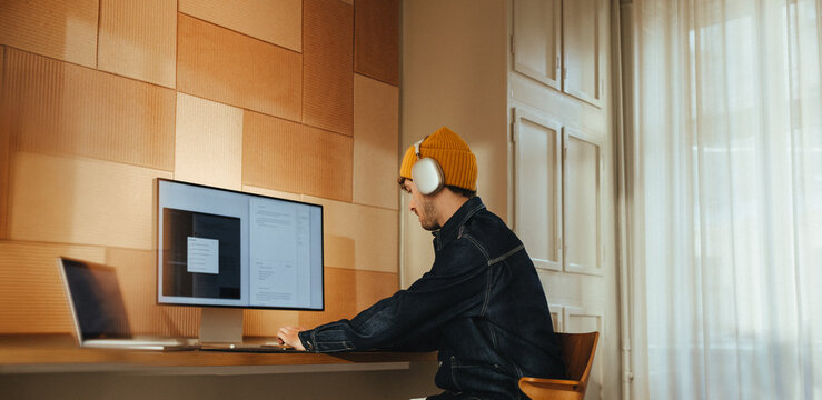 Focused man wearing headphones working at desk in office space