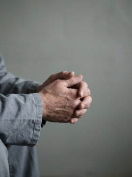 Close-up of man with clasped hands. Anxiety and prayer gesture expressing stress, hope and contemplation. Mental health and emotional support concept with copy space.
