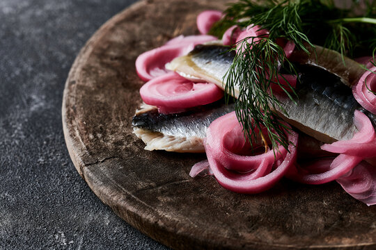 Gourmet pickled red onion with herring and fresh dill on wooden board