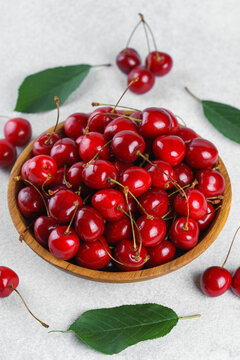 Fresh ripe sweet cherries in rustic wooden bowl on white stone textured background with copy space for text. Juicy organic summer fruit, red berries, healthy seasonal food, farm harvest