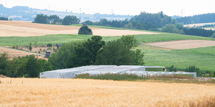 Construction site, preparation for building wind turbine farm, concrete tower section, foundation area, rows of curved segments, gravel ground in forest, Germany