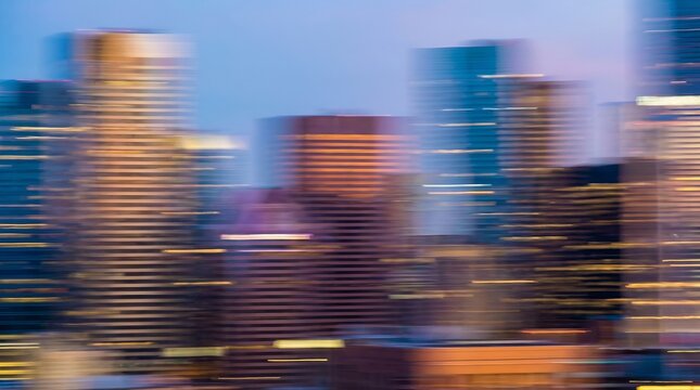 Blurry city skyline at dusk, with illuminated skyscrapers and a hazy sky