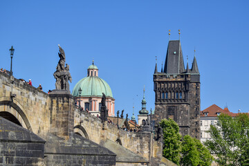 Fototapeta premium A scenic view of Prague’s historic Charles Bridge, with Old Town Bridge Tower and St. Francis church dome in background