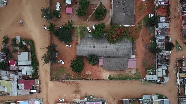 Slow aerial flight over a hospital compound in Maputo, Mozambique, showing surrounding dirt roads, buildings, vehicles and dense urban settlement.