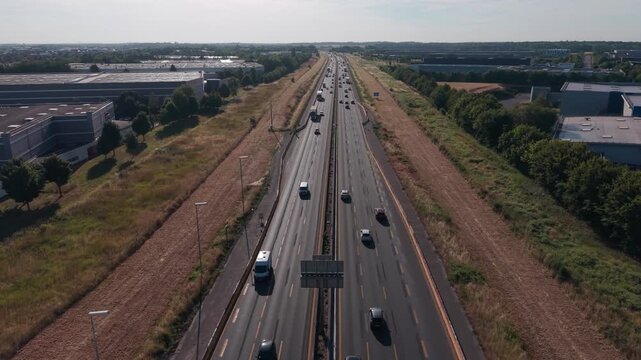Static aerial overlooks busy motorway traffic beside parallel railway tracks.