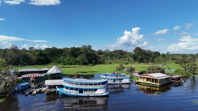 Aerial footage of a traditional multi-level riverboat cruising on the Amazon River surrounded by dense green rainforest in Brazil.