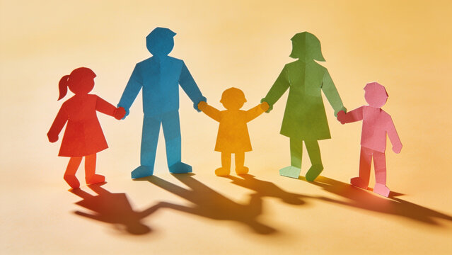 Colorful paper cutouts representing a happy family holding hands together against a bright warm orange background