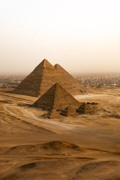 The famous Giza pyramids in the desert in Egypt as seen from a bird eye while flying. Beautiful desert scene, there is a desert storm and the air seems orange