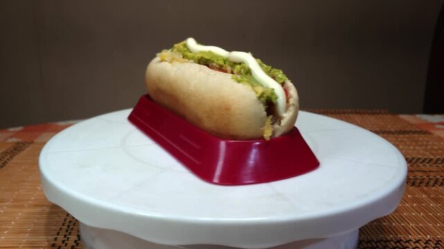 Chilean hot dog completo italiano with avocado, tomato and mayonnaise rotating on a turntable, traditional Chilean street food and popular fast food