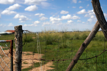 Fototapeta premium Wooden Fence and Barbed Wire Under Bright Blue Sky