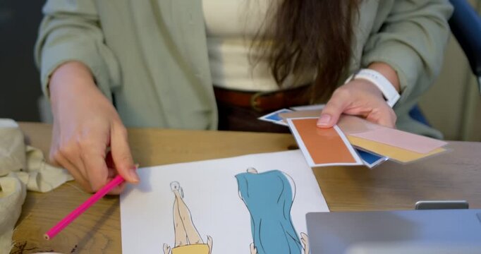 Designer is picking pink marker, coloring left figure at desk, fanning swatches to select palette