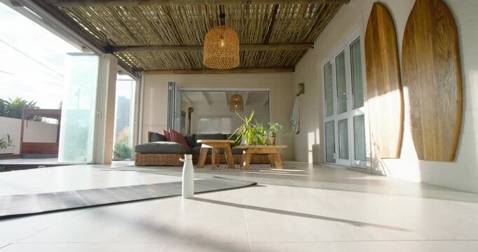 Camera is pulling back, panning to reveal veranda while water bottle is remaining upright on tile