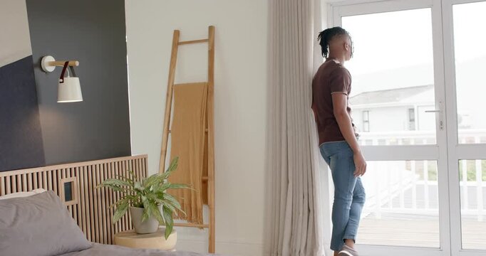 Man is stepping and peering through glass door, drawn by bright exterior, checking balcony view