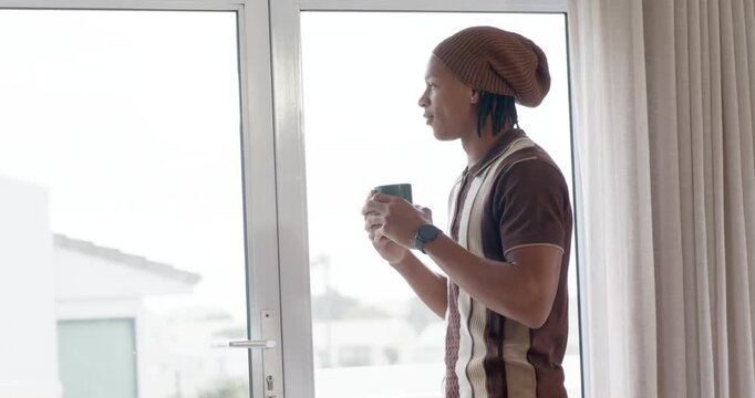 African American man gazing outside by glass door, raising mug to savor aroma, sipping, copy space