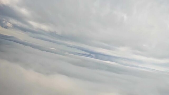 The view from the parachute is of an endless layer of clouds and other parachutists in the distance. Atmospheric flight at high altitude.
