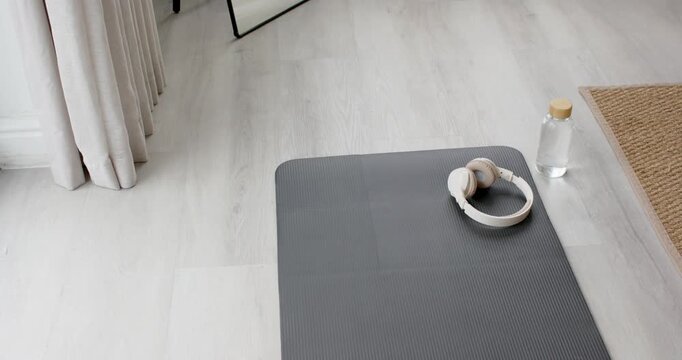 Camera is recording dark gray mat with beige headphones resting, showing prepared workout corner