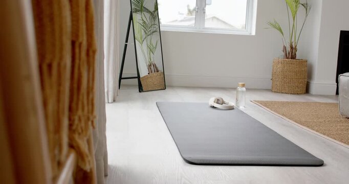 Camera is moving forward revealing gray mat with headset and water bottle to show workout corner