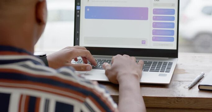Placing hands on keyboard, man is typing reply on laptop at wooden table, purple bubble updating