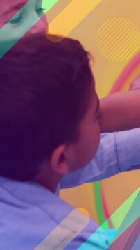 Children drawing on chalkboard, colorful shapes animation over classroom background