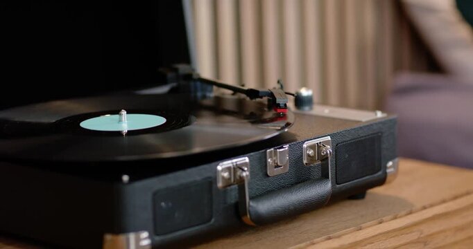 Record player is spinning vinyl after tonearm drop, stylus tracking and playing music on wood table