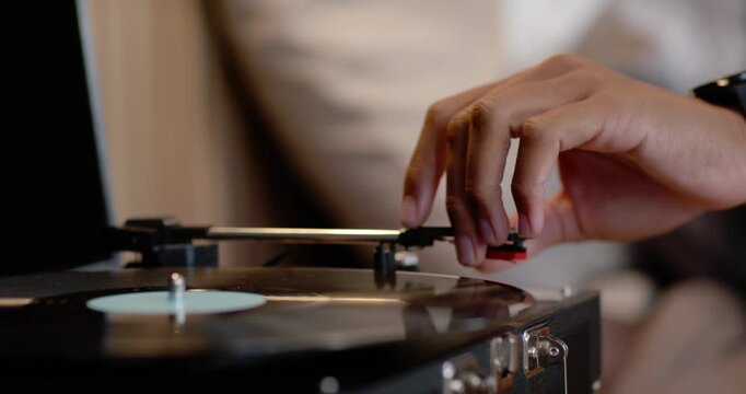 Right hand is cueing stylus, lowering tonearm onto spinning vinyl on case turntable, refining sound