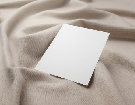 Blank white card mockup template on beige textile folds