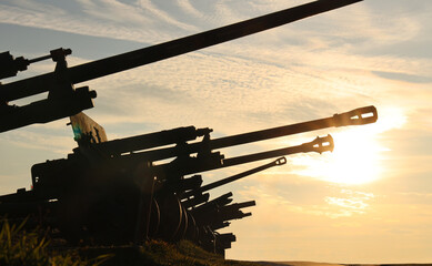 Fototapeta premium Cannons silhouetted against a stunning sunset, the scene exudes a sense of historical grandeur strength. positioned in a row perspective, bathed in the warm glow of the setting sun World war II 2 two