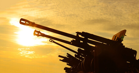 Naklejka premium Cannons silhouetted against a stunning sunset, the scene exudes a sense of historical grandeur strength. positioned in a row perspective, bathed in the warm glow of the setting sun World war II 2 two