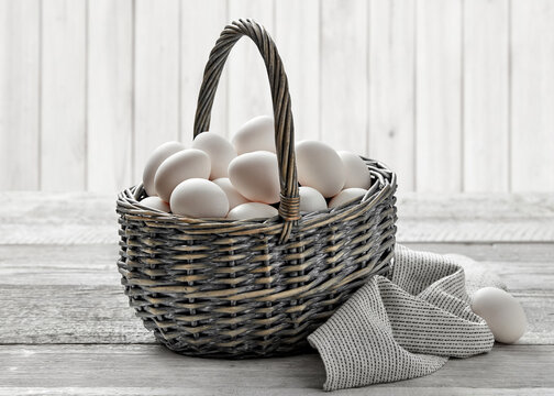 white eggs in rustic wicker basket on wooden table