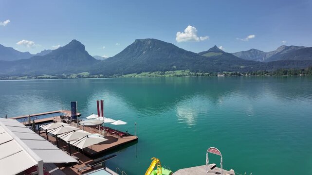 Picturesque alpine lake resort with crystal clear water and umbrellas at St. Wolfgang, Salzkammergut