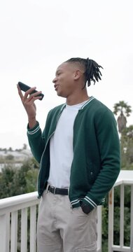 Vertical video: Man holding smartphone to mouth and speaking on balcony, making call