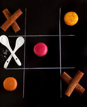 Tic-tac-toe made with cinnamon sticks, spoons of salt and macarons