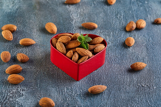 Almonds in red in the form of a heart, on a background with a blue tint. Concept for valentines day