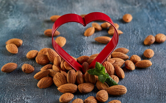 Almonds in red in the form of a heart, on a background with a blue tint. Concept for valentines day
