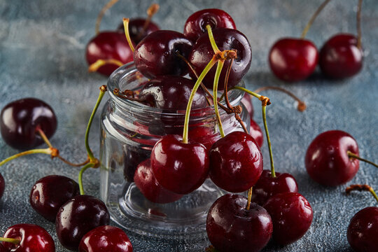 Fresh Cherry or sweet cherry with water drops lying on a background with a blue tint.
