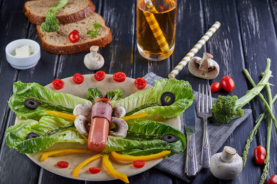 Healthy dietary breakfast vegetables on a plate - leaves of khasa, cherry tomatoes, paprika, esparagus, olives laid out in the shape of a butterfly and a glass of apple juice