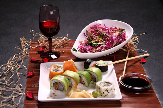 Lunch with wine, sushi and chop stik on wooden stand, on gray background.