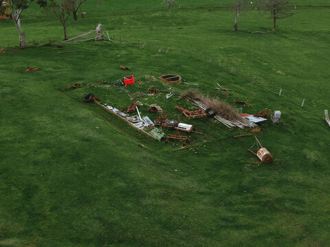 Aerial view of abandoned farm equipment and scrap metal scattered on a green grassy field in Ferntree Gully, Victoria, Australia.