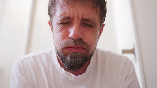 Close-up of distressed man sitting on toilet and struggling during bowel movement, with tense facial expression, illustrating bathroom discomfort, constipation and digestive health concerns.