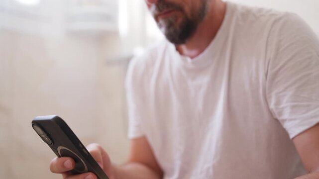 Middle-aged man sitting on toilet and looking at smartphone during a private bathroom moment, depicting adult self stimulation, personal habits and private digital entertainment.