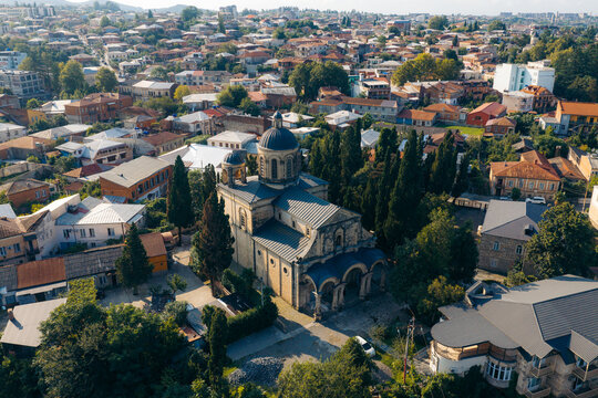 Aerial view of the historic Bagrati Cathedral surrounded by lush trees and the urban landscape of Kutaisi, Imereti, Georgia.