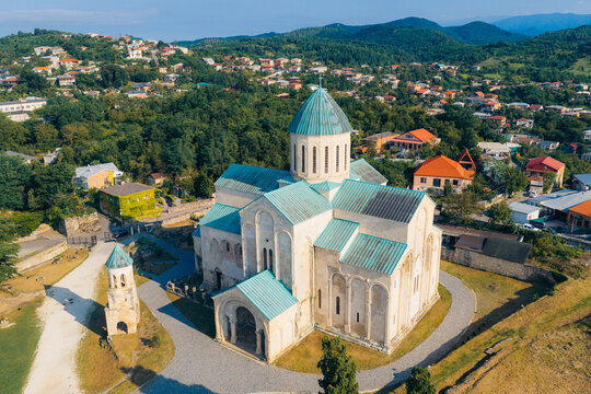 Aerial view of the historic Bagrati Cathedral with its distinctive green copper roof and stone architecture, surrounded by the residential landscape of Kutaisi, Imereti, Georgia.