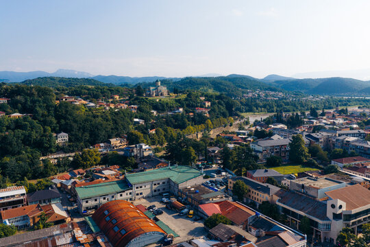 Aerial view of the historic Bagrati Cathedral perched on a hill overlooking Kutaisi, with surrounding rooftops, lush trees, and the Rioni River, Kutaisi, Imereti, Georgia.