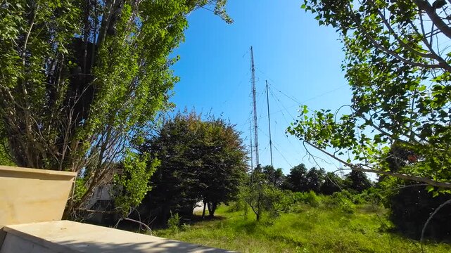 Radio Communication Antenna Tower in a Green Landscape Under Clear Blue Sky