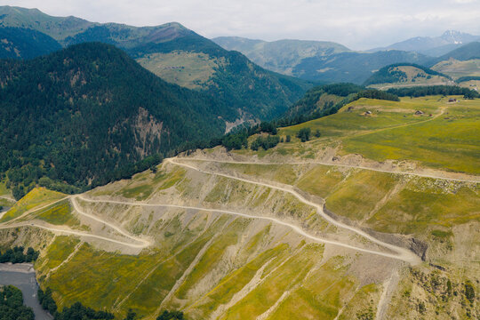 Aerial view of the winding dirt road of Abano Pass cutting through the steep green slopes and mountain landscape of Akhmeta Municipality, Kakheti, Georgia.