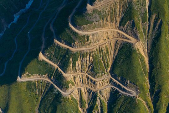 Aerial view of the winding dirt road of Abano pass cutting through steep green mountain slopes in Akhmeta Municipality, Kakheti, Georgia.